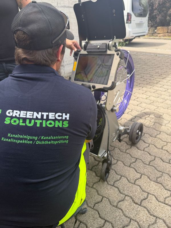 Blick über die Schulter eines Greentech-Technikers auf den Monitor der Rohrkamera